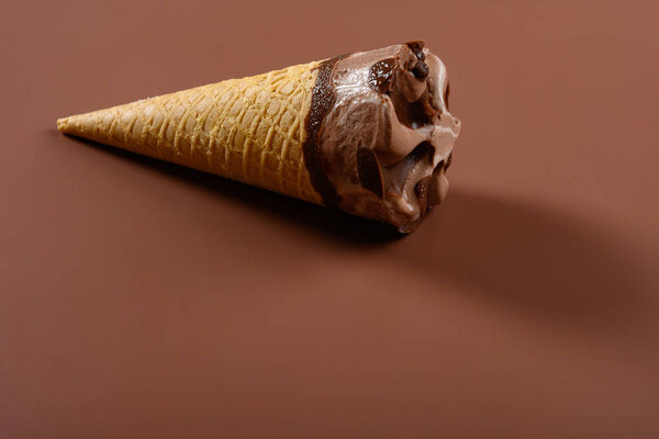 Конус мороженого со вкусом шоколада и кофе на коричневом фоне
