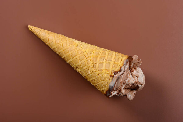 Кофе и шоколадное мороженое с парой укусов на коричневом фоне
