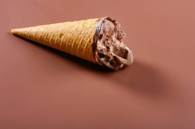 yan görünüm kahve ve çikolata lezzet dondurma koni kahverengi arka plan üzerinde bazı ısırıklar ile