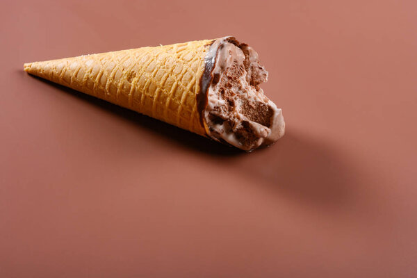 вид сбоку кофе и шоколадное мороженое конус с некоторыми укусами на коричневом фоне
