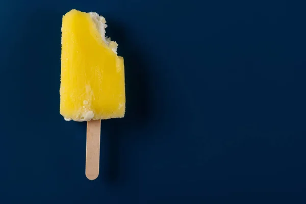Half Gegeten Gele Popsicle Een Donker Blauwe Achtergrond — Stockfoto