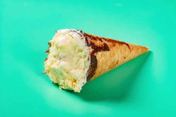 side view mango and chocolate flavor ice cream cone with some bites on light green