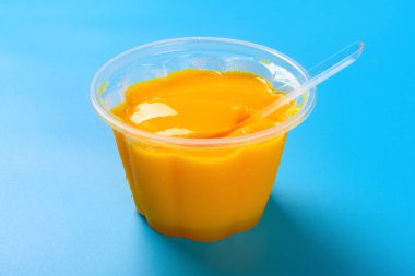 yan görünümü mavi bir arka plan üzerinde bir kaşık ile ev yapımı mango lezzet puding