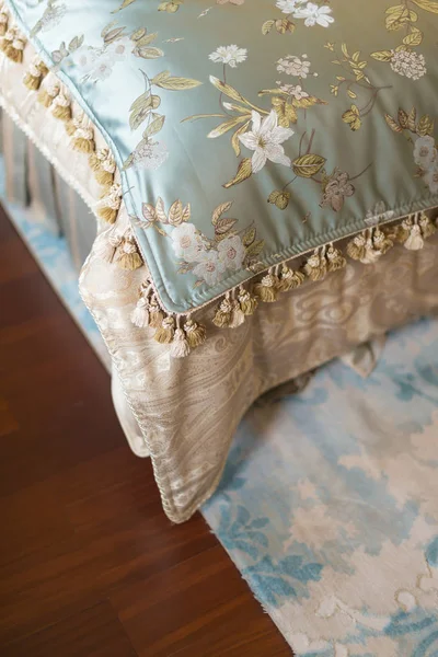 corner of a bed with carpet on wood floor in a bed room