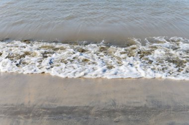 Kumlu bir sahilde yumuşak dalgalar