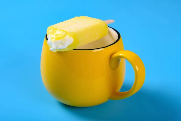 Moitié Mangé Glace Jaune Sur Une Tasse Sur Fond Bleu — Photo