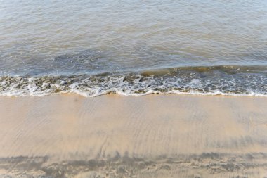 Kumlu bir sahilde yumuşak dalgalar
