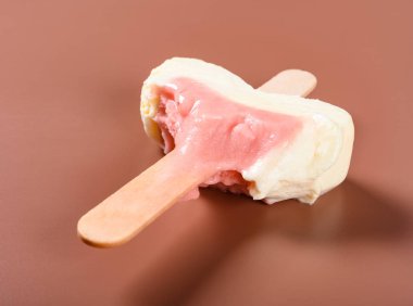 Yan görünüşlü çilek aromalı dondurmanın son parçası kahverengi arka planda.