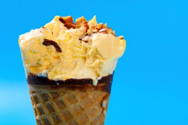 Mango ve çikolata aromalı dondurma külahına yakın. Fıstıklı ve mavi arka planda.