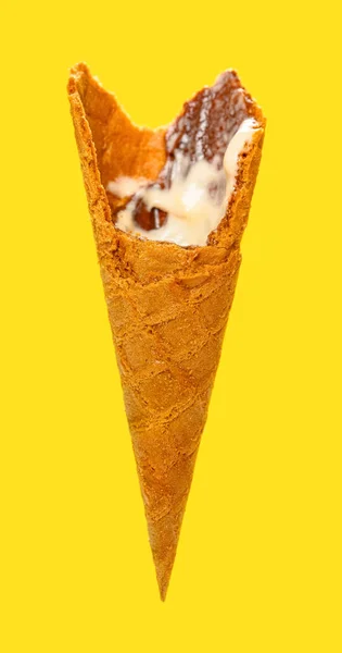 サイドビューは主に黄色の背景にバニラ風味のアイスクリームコーンを食べました — ストック写真