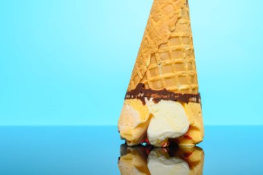 Taze vanilya ve çilek aromalı dondurma külahı bir bardağın üzerinde baş aşağı duruyor.