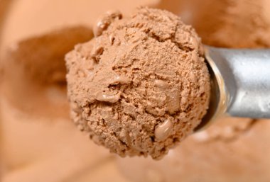 Üst kaşık çikolatalı dondurma kutusundan dondurma topunu çıkarıyor.