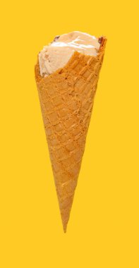 Yan manzara sütlü çay aromalı dondurma külahı ve sarı arka planda ısırıklar.