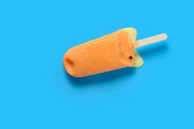 En üstteki turuncu renkli çikolatalı buzlu şekerleme mavi arka planda erimeye başlar.