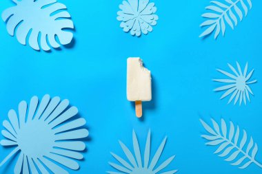 Üst manzara, yarı pişmiş peynir aromalı buzlu dondurma, üzerinde mavi bir ısırık, el yapımı çiçek ve yapraklar.