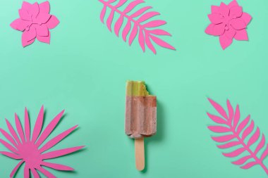 Kırmızı fasulye ve yeşil çay aromalı buzlu şekerleme. Üzerinde kağıt, çiçek ve yeşil arka planda yapraklar var.