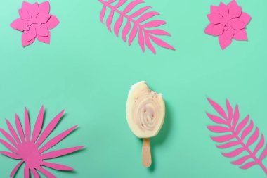 Üst görünüm kırmızı jube ve süt aromalı lolipop kağıt parçalı ve yeşil arka planda yapraklar kesiyor.