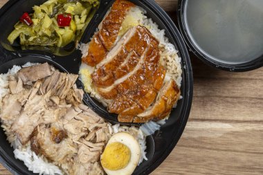 Bölünmüş bir konteynırda lezzetli bir Asya yemeği sunuluyor, kızarmış ördek, haşlanmış domuz eti, sebze turşusu ve haşlanmış yumurta, yanında da temiz bir çorba.