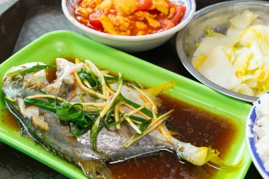 Üst görünüm gümüş pomfret, karışık pirinç, karıştırılmış domates ve çırpılmış yumurta içeren dengeli bir Asya yemeği, yatay kompozisyonda bir tepside servis edilir.