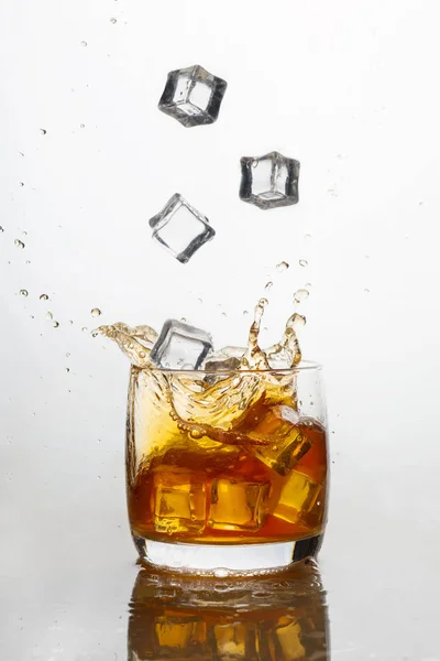 Whisky mit Eis im Glas mit Spritzern — Stockfoto