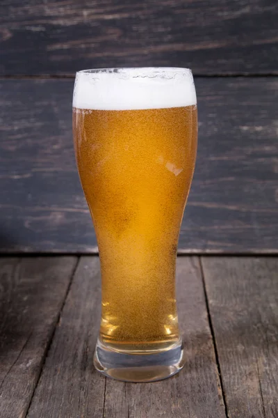 koyu ahşap masa üzerinde bir bardak fıçı bira Lager