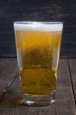 koyu ahşap masa üzerinde bir bardak fıçı bira Lager