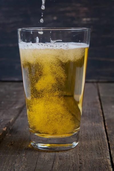 koyu ahşap masa üzerinde bir bardak fıçı bira Lager