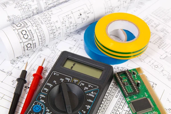 Electronics and Engineering. Printed drawings of electrical circuits, digital multimeter, electronic board and insulating tape.