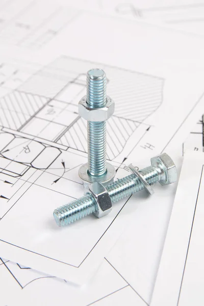 Technical drawings of bolt and nut. Engineering, technology and metalworking. Metal bolt and nut on printed drawings background.
