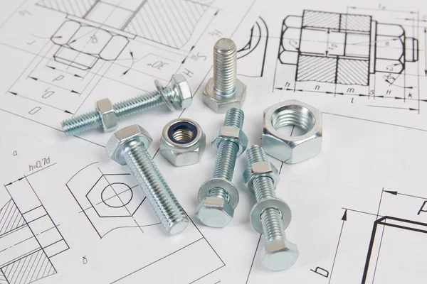 Technical drawings of bolt and nut. Engineering, technology and metalworking. Metal bolt and nut on printed drawings background.