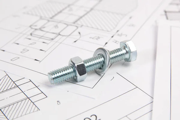 Technical drawings of bolt and nut. Engineering, technology and metalworking. Metal bolt and nut on printed drawings background.