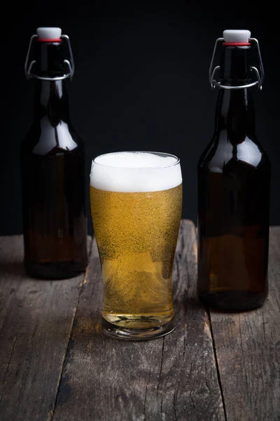 siyah bir arka planda bir bardak lager bira ve bir şişe