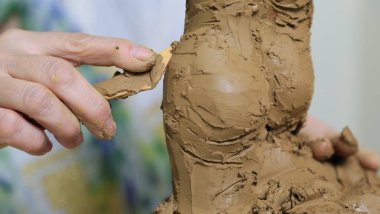 Heykeltıraş heykelin kenarını yontmak için araç kullanır. Heykeltıraş iş başında..