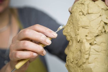 Heykeltıraş heykelin kenarını yontmak için araç kullanır. Heykeltıraş iş başında..