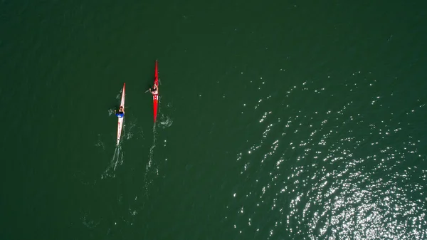 Aerial drone bird's eye view of sport canoe operated by team of young men in green sea waters. Aerial view of rowing team in Mugla  Turkey