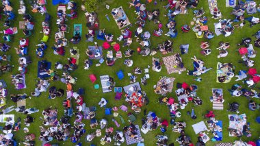 Bir yaz günü şehir parkındaki insanların Ankara / Türkiye 'deki piknik halılarında otururken, ayakta dikilirken genel görünümü