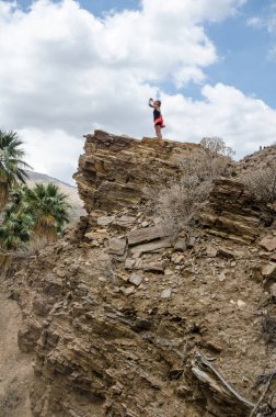 Uzun bir yürüyüş sırasında sıcak bir günde bir su içme Palm Springs Kanyonu'bir uçurumun üzerinde uygun aktif kadın uzun yürüyüşe çıkan kimse duruyor