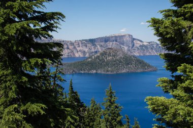 Görünümü Sihirbazı adasının üzerinde Oregon'da, çam ağaçları ile bir yaz gününde çerçeveli Krater Gölü Milli Parkı