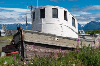 Güneşli bir günde Alaska'da Homer Spit boyunca araba mezarlığı terk edilmiş batık oturuyor