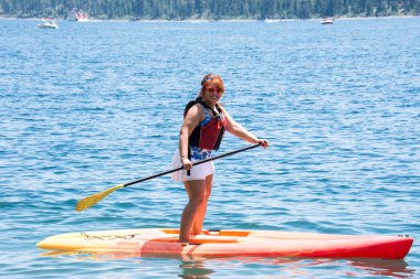 Aktif kadın (20'li) satırları paddleboard Lake Tahoe üzerinde ayağa yaz aylarında uygun.