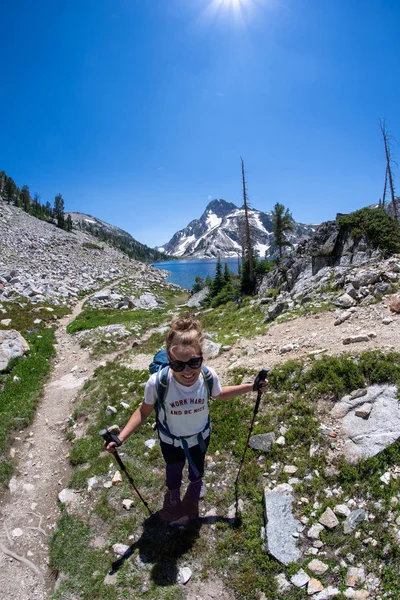 Woman hiker stands on the trail of Sawtooth Lake in Idaho's Sawtooth Mountain Range in the Salmon-Challis National Forest near Stanley Idaho.