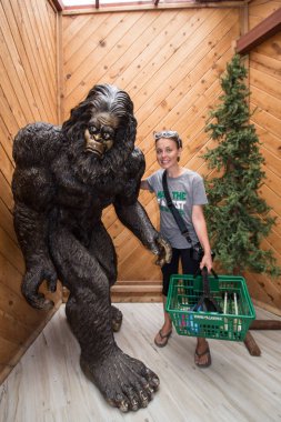 11 Temmuz 2017 - Klamath, Ca: gizem ağaç Hediyelik Dükkanı dev Bigfoot yanında duruyor, alışveriş sepeti tutan bir yetişkin erkek / Sasquatch heykel mağaza içinde bulunan Redwoods