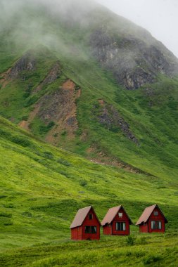Alaska'nın Hatcher Pass yakınındaki bağımsızlık benim yeşil yemyeşil Dağları'nda terk edilmiş kırmızı kabin oturmak.