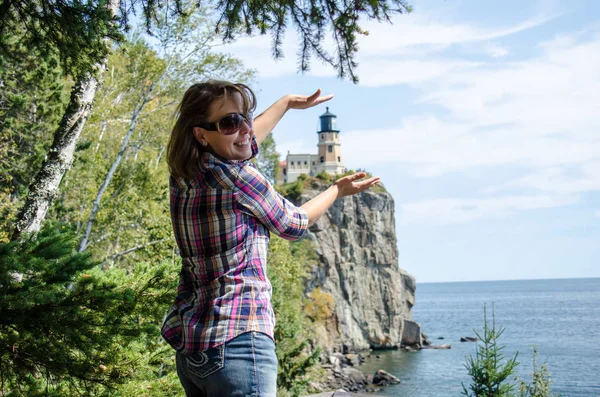 Forced perspective view of a pretty female appearing to be holding the Split Rock Lighthouse in Minnesota with her hands