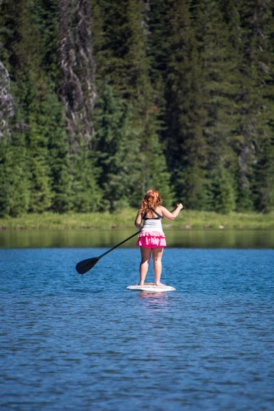 在炎热的夏天 成年女性站在湖面上的一个索普 站起划桨板 — 图库照片