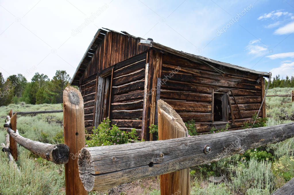 Abandoned log cabin with a dirt trail in Miners Delight Wyoming, a former mining town and camp, now a ghost town