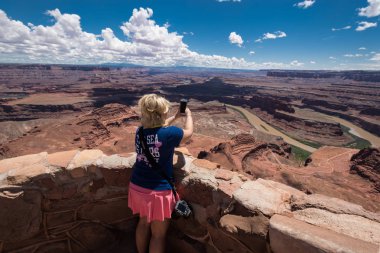 8 Mayıs 2018 - Moab, Utah: Yetişkin bir kadın turist pahalı bir Nikon Dslr fotoğraf makinesi taşıyan rağmen onun cep telefonu, fotoğraf, Canyonlands Milli Parkı alır