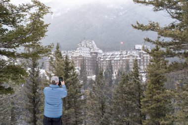 Banff, Kanada - 21 Ocak 2019: Erkek turist bir kış sahne görünümünü ünlü Fairmont Banff Springs Hotel, Banff Ulusal Parkı'nda sürpriz köşesinden bir smartphone ile görüldüğü gibi fotoğraf arşivi