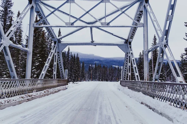 Winter scene of a bridge crossing the Bow River on the snow covered, icy Bow Valley Parkway in Banff National Park Canada
