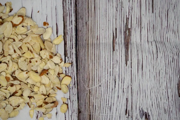 Slivered badem hafif ahşap arka plan üzerinde sol tarafında bir yığın. Yararlı bilgi ve afiş ilave kopya alanı ile